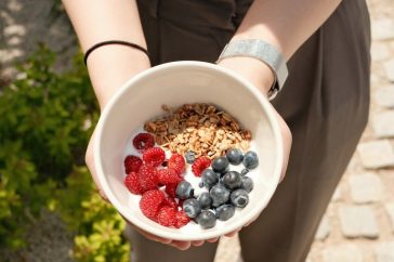 a person holding a bowl of cereal and berries