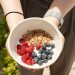 a person holding a bowl of cereal and berries